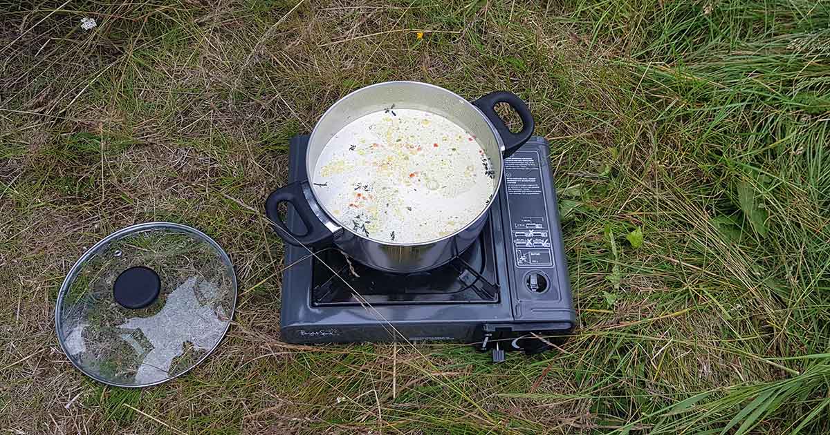 Verwertung von Lebensmitteln in der Campingküche: Topf mit Suppe auf Campingkocher.