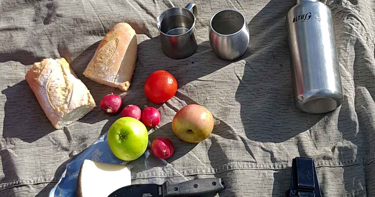 Snackidee für Wanderpausen: Brot, Käse, Tomaten, Radieschen, Äpfel und Wasser.