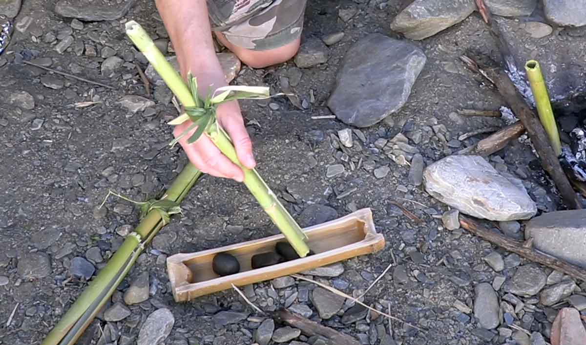 Wasser kochen in Bambustopf mit heißen Steinen